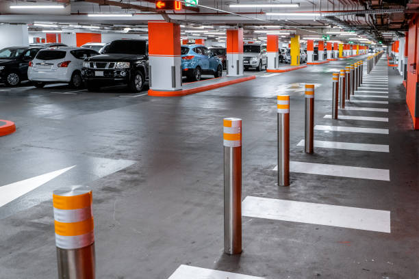 istock Parking garage underground interior, pedestrian crossing. Illuminated underground car parking interior under modern mall with lots of vehicles and arrows on floor 1312590911