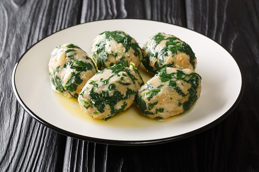 Italian Strangolapreti spinach dumplings with butter sage sauce close-up on a slate board on the table. horizontal