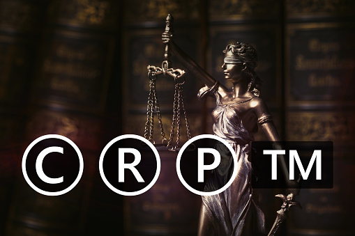 Concept of copyright, patent and registered trademarks law. Figurine of Themis symbolizing justice and law.