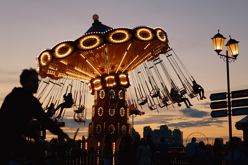 Silhouette of the carousel against the background of the sunset. In the foreground is the silhouette of a cyclist.