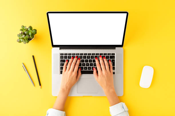 istock Female hands working on laptop with copyspace on yellow background with business accessories. Top view 1312597799