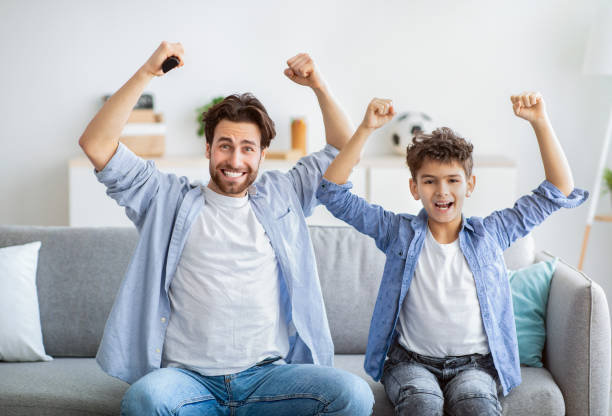 istock Hooray. Emotional father and son supporting favorite team, cheering for victory while watching sports on TV 1312597996