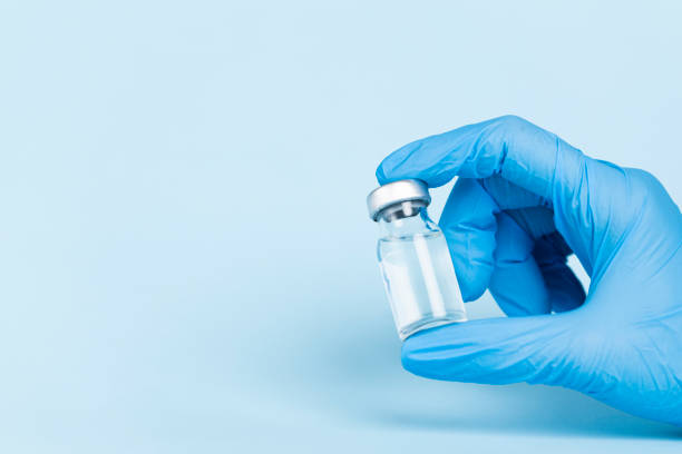 istock Hand in protective glove holds vaccine glass vial 1312598626