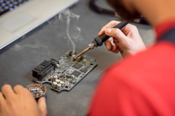 istock Hands of man with soldering iron and microcircuit 1312598820