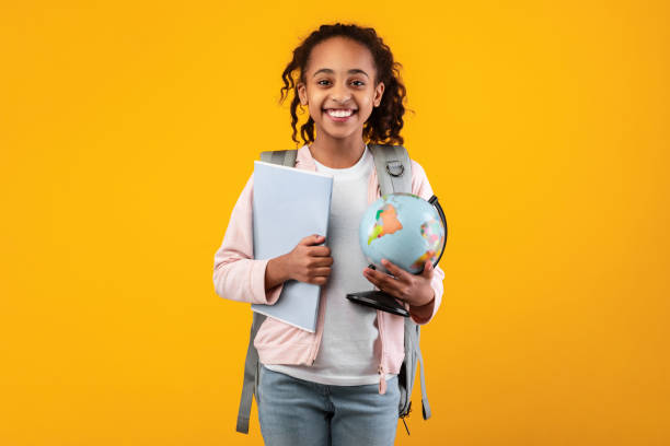 веселая молодая черная девушка, держащая земной глобус и блокнот - schoolgirl school children isolated child стоковые фото и изображения