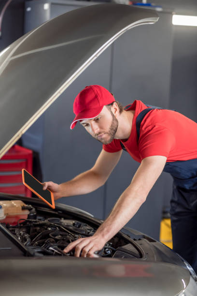 istock Auto mechanic with tablet examining car under hood 1312599543