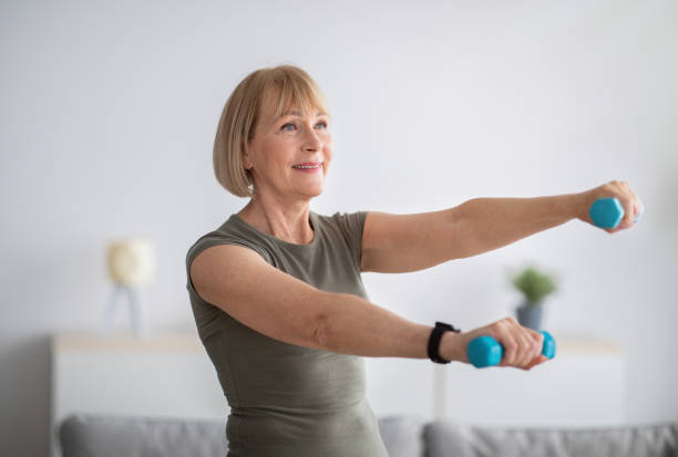 istock Joyful senior woman doing domestic training, working out with dumbbells, exercising her biceps at home 1312601068