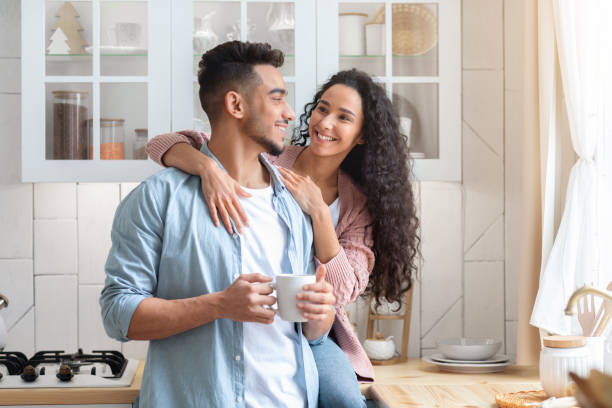 istock Happy Young Arab Spouses Hugging And Drinking Coffee In Cozy Kitchen Interior 1312601167