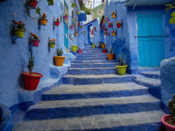 Chefchaouen the Blue city in Morocco -The blue staircase with colours flowers and vases stock photo