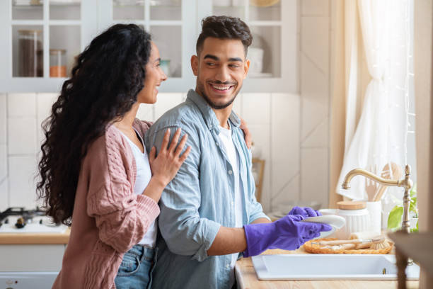 istock Loving Arab Wife Embracing Her Husband While He Washing Dishes In Kitchen 1312601320