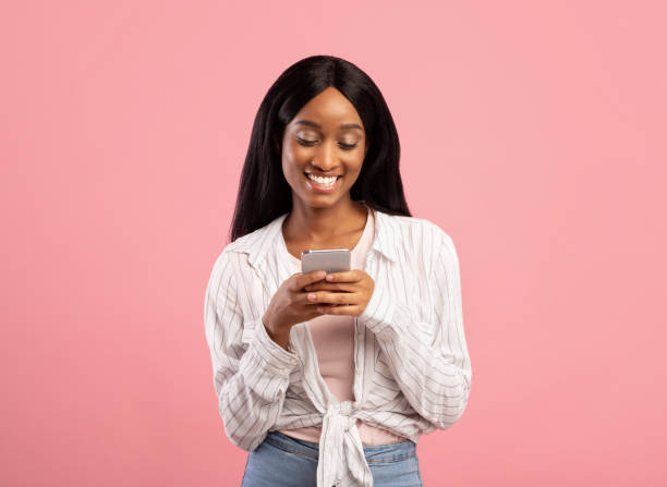 istock Pretty young black woman surfing web on smartphone on pink studio background 1312601386