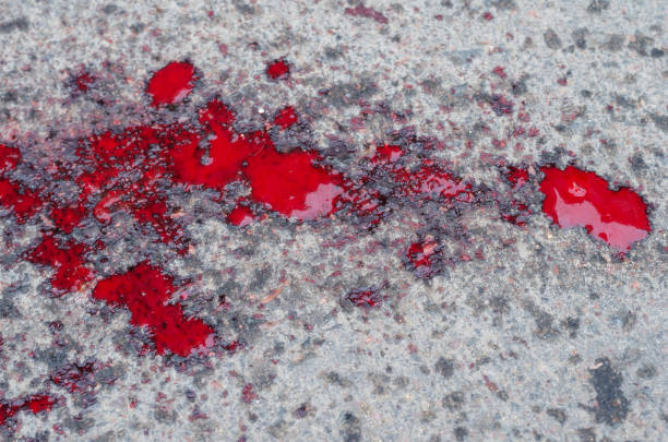 A pool of blood on the asphalt. Splattered human blood on the road. Top view at an angle.