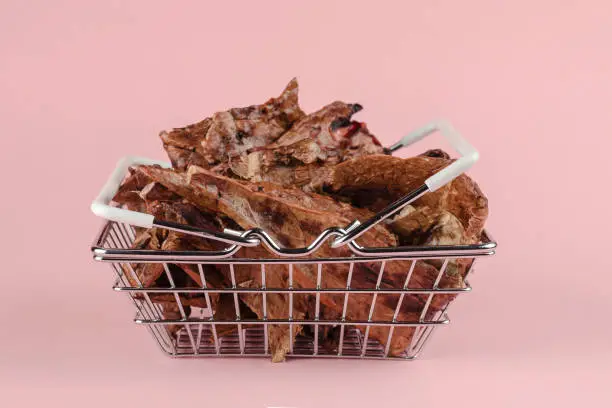 Photo of Shopping basket with dog treats on a pink background. Natural tr