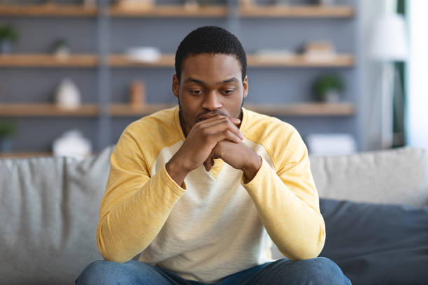 istock Upset black man having problems, sitting on couch at home 1312602195
