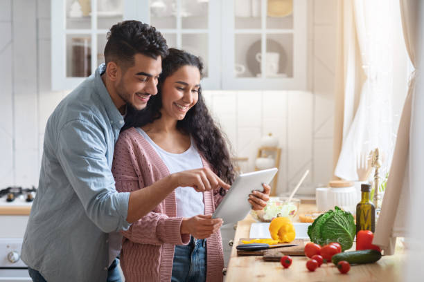 istock Cheerful Arab Couple Using Digital Tablet While Cooking Healthy Lunch In Kitchen 1312602246
