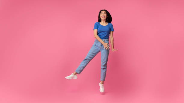 istock Happy young asian lady jumping at pink studio, panorama 1312602286
