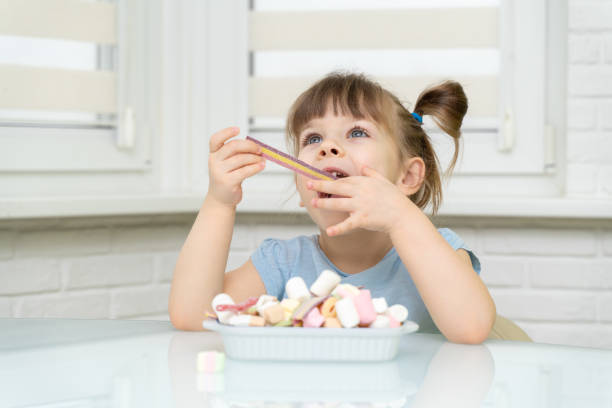 istock girl sitting at the kitchen table and eating sweets 1312602525