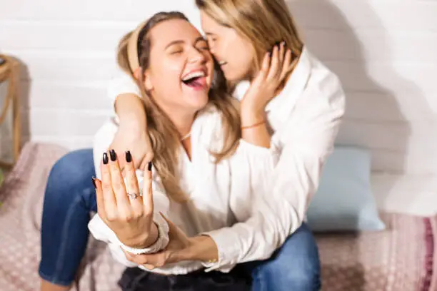 Cinematic defocus shot of a happy homosexual couple, two beautiful women are happy. Gay couple marriage proposal concept, love is love, wedding ring, engagement day