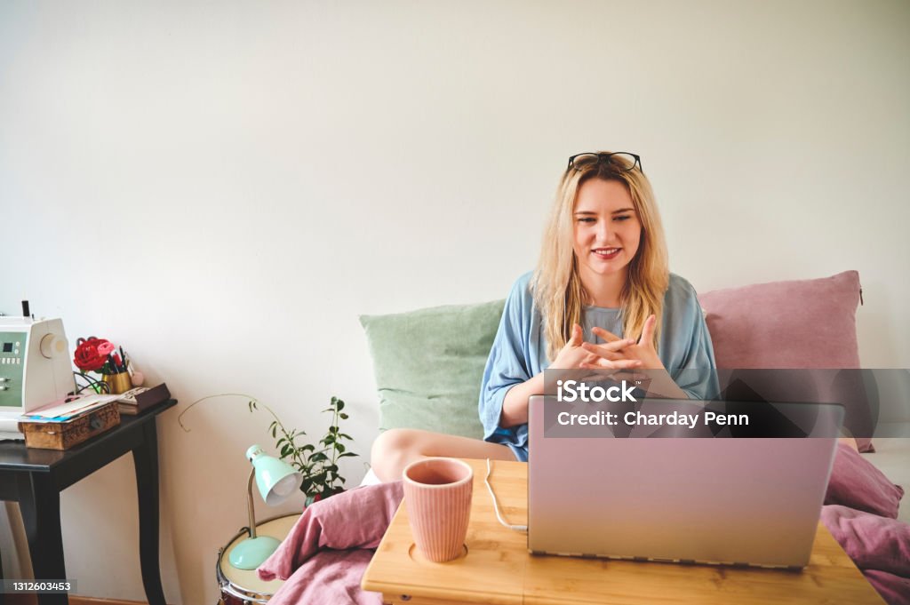 I'm literally working in my comfort zone Cropped shot of an attractive young woman sitting up in bed and working on her laptop at home 20-29 Years Stock Photo