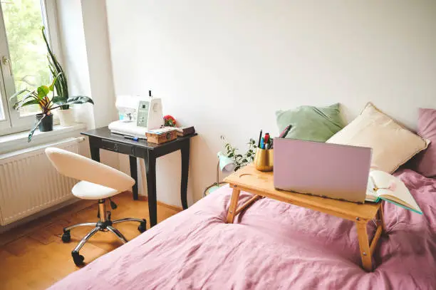 Cropped shot of a laptop and bedroom furniture in an empty room during the day
