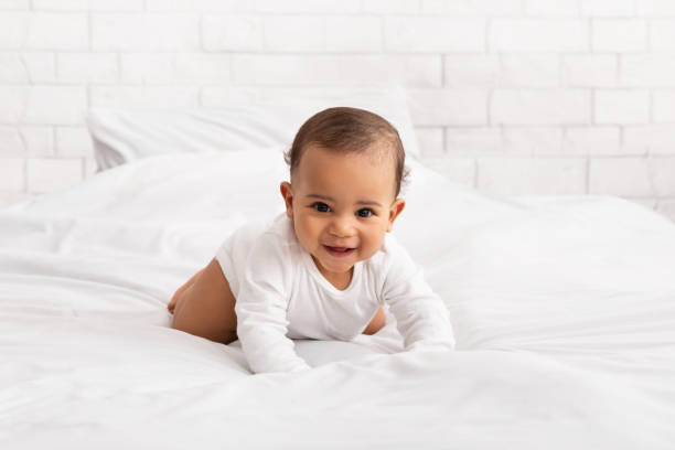 istock Black Baby Crawling On Bed Smiling To Camera In Bedroom 1312603632