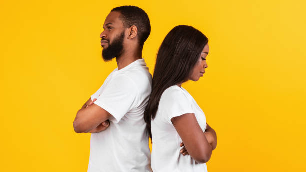 istock Black couple standing back to back, yellow studio wall 1312603689