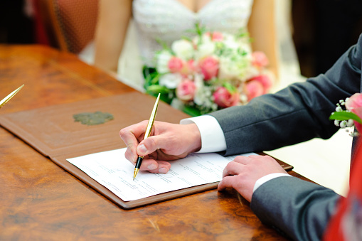The groom puts his signature in the marriage document.
