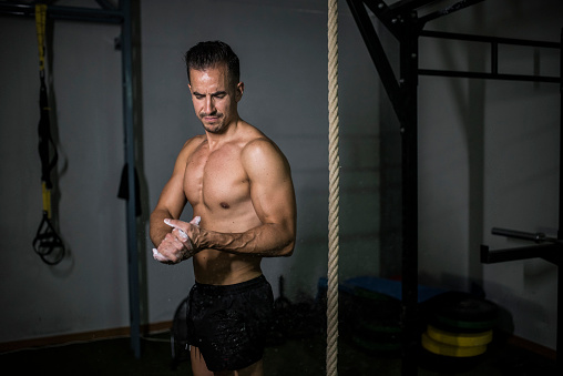 man preparing hands with chalk for train climbing the rope at gym