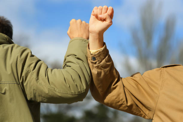 istock People greeting each other by bumping elbows instead of handshake outdoors, closeup 1312607865