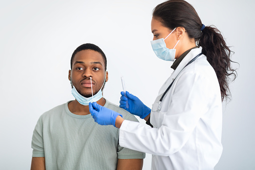 Enfermera haciendo prueba de PCR para hombre afroamericano, fondo blanco photo