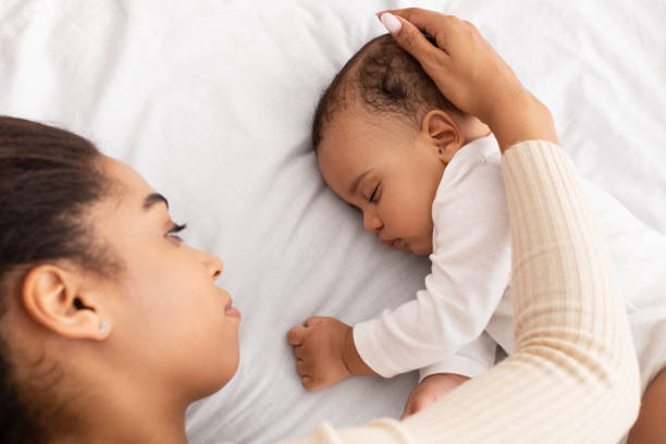 istock African Mom Stroking Sleeping Baby Lying In Bed Indoor 1312608327