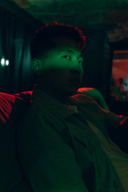 istock Young Korean man with tablet at home interior in gradient red green neon light 1312608414