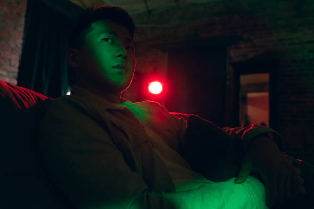 istock Young Korean man using tablet at home interior in gradient red green neon light 1312608422
