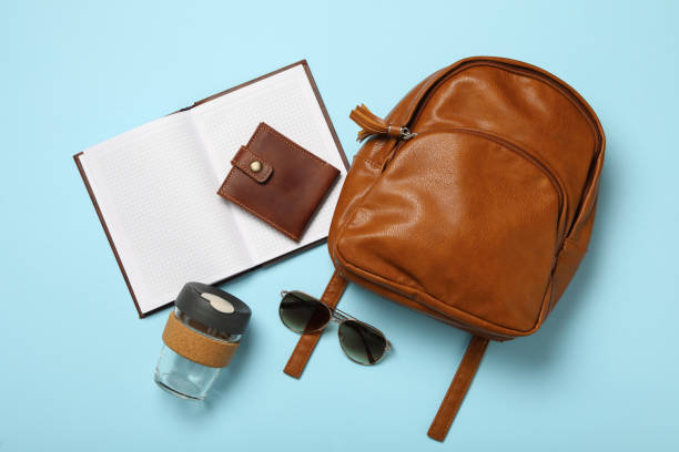 istock Stylish urban backpack with different items on light blue background, flat lay 1312609400
