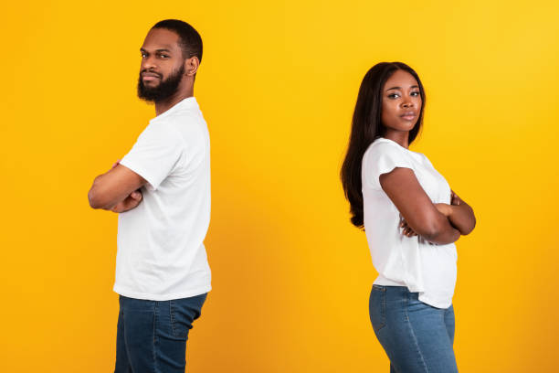 istock Black couple standing back to back, yellow studio wall 1312609592