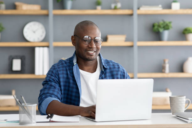 istock Freelance career. African american man working on laptop computer, doing new project, sitting at home workplace 1312610814
