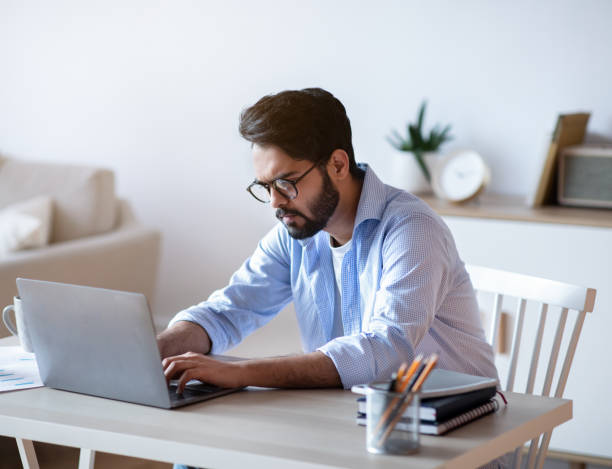 istock Arab Freelancer Guy Sitting At Desk At Home And Typing On Laptop 1312610873