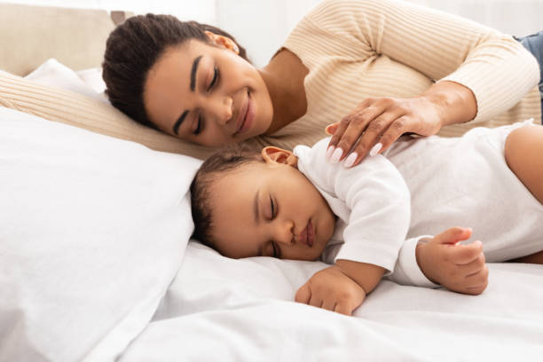 istock Loving Black Mom Hugging Sleeping Baby Lying In Bed Indoor 1312610896