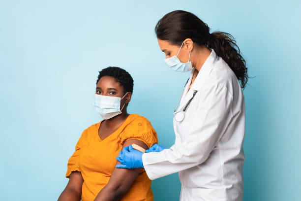 istock Nurse Vaccinating African Patient Applying Bandage On Vaccinated Arm, Studio 1312611173