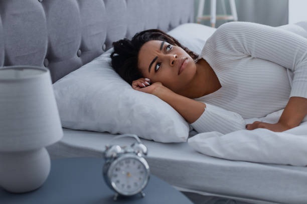 Black woman suffering from insomnia looking at ceiling Lack Of Sleep Concept. Stressed young African American woman suffering from insomnia, lying in bed, waking up throughout the night, feeling depressed about start of the working week horror waking up bed women stock pictures, royalty-free photos & images