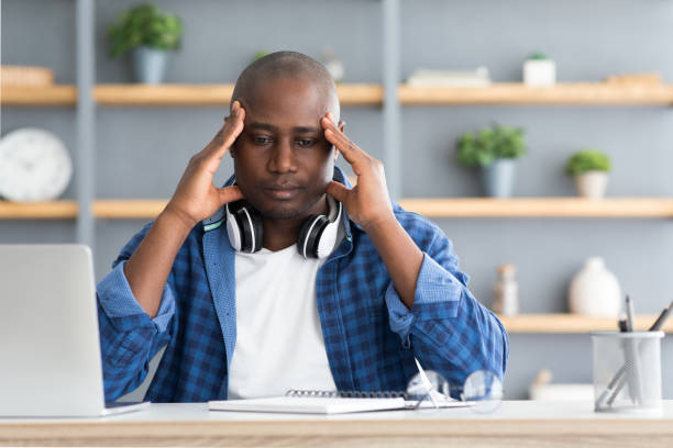 istock Migraine attack. African american man suffering from headache at workplace while working on laptop 1312612078
