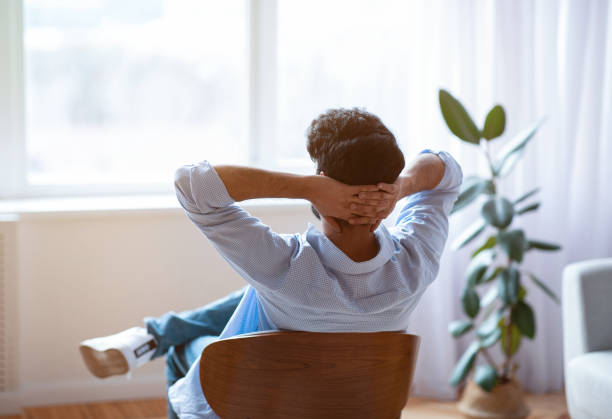 istock Unrecognizable man relaxing on chair at home with hands behind head 1312612093