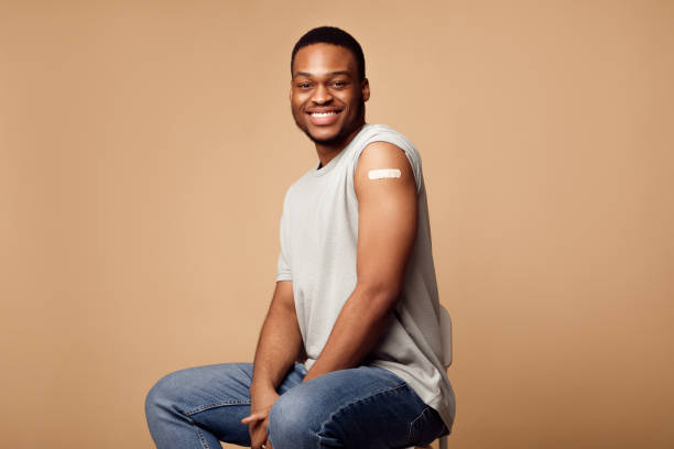istock Cheerful Vaccinated Black Man Showing Arm Posing Over Beige Background 1312613323