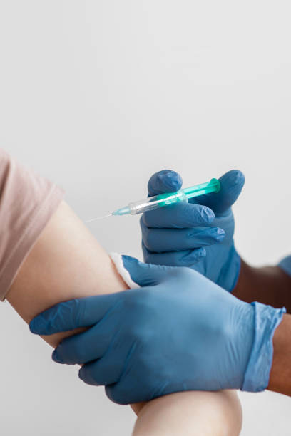 istock Coronavirus covid-19 immunization vaccination campaign. African american doctor in protective gloves giving injection 1312613509