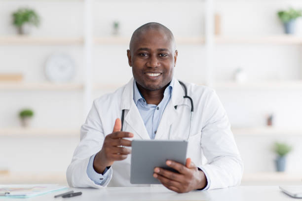 istock Online consultation. Cheerful black doctor using digital tablet at his office, talking with patients distantly during quarantine. 1312613774