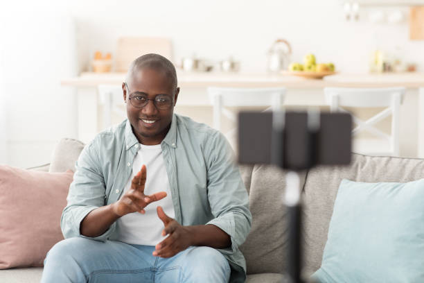 istock Black mature blogger talking and gesturing to mobile phone camera, broadcasting from home 1312613974