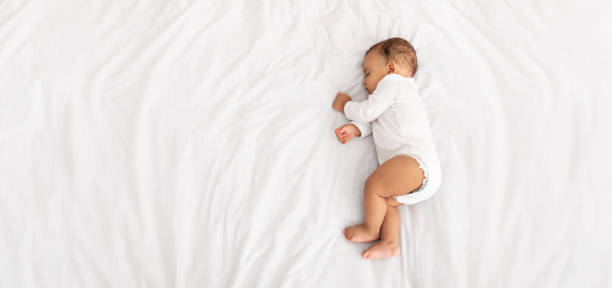 bambino che dorme sul lato sdraiato a letto all'interno, ad angolo alto - sleeping baby foto e immagini stock