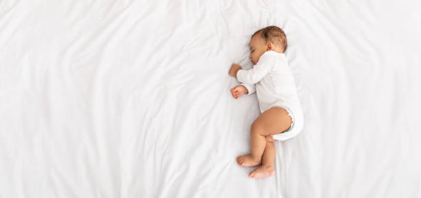 屋内でベッドに横たわっている側に眠っている男の子、高角 - sleeping baby ストックフォトと画像