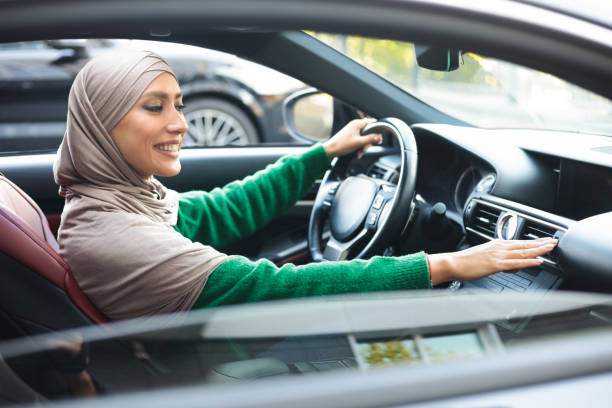 mulher muçulmana alegre dirigindo carro, verificando ar condicionado - arab style audio - fotografias e filmes do acervo