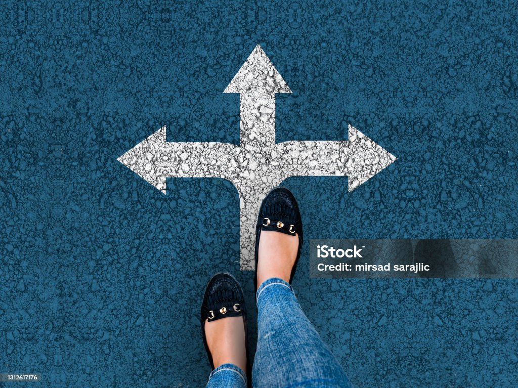 woman legs in shoes standing on road with three direction arrow legs and three direction arrow choices, left, right or move forward Crossroad Stock Photo
